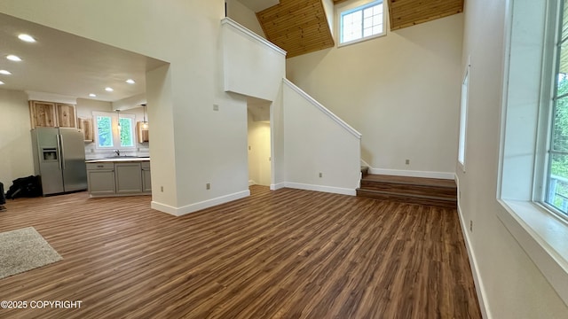 9742 W Trimotor St, Wasilla, AK 99623 - unfurnished living room featuring recessed lighting, baseboards, dark wood-style floors, plenty of natural light, and a towering ceiling