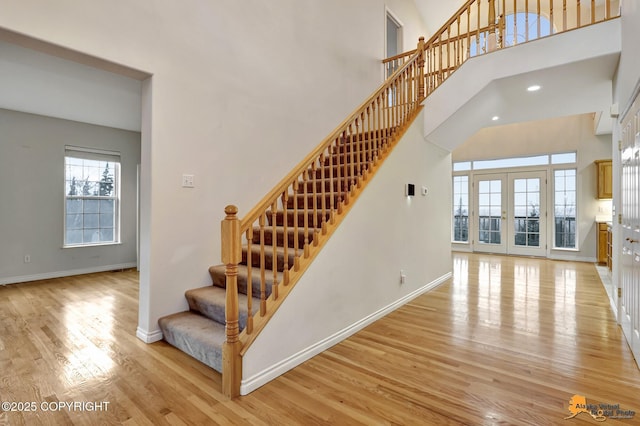 stairs featuring a high ceiling, wood-type flooring, and french doors