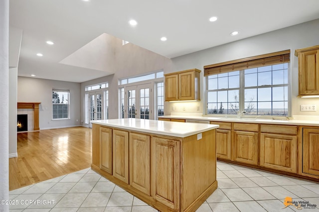 kitchen featuring a center island, french doors, a fireplace, plenty of natural light, and light tile patterned floors