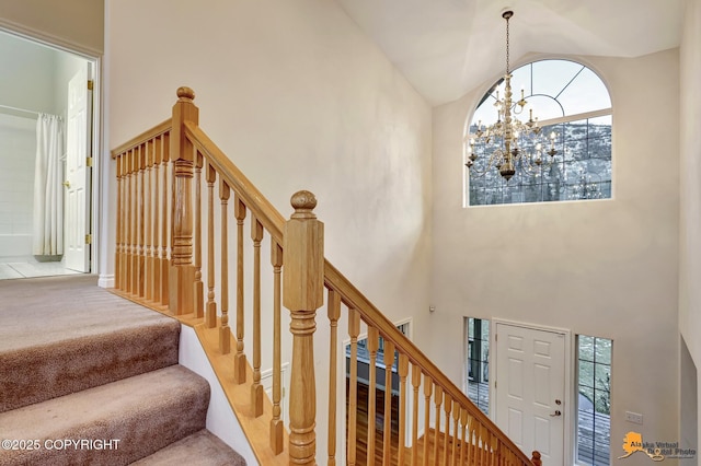 staircase with high vaulted ceiling, carpet floors, and a notable chandelier