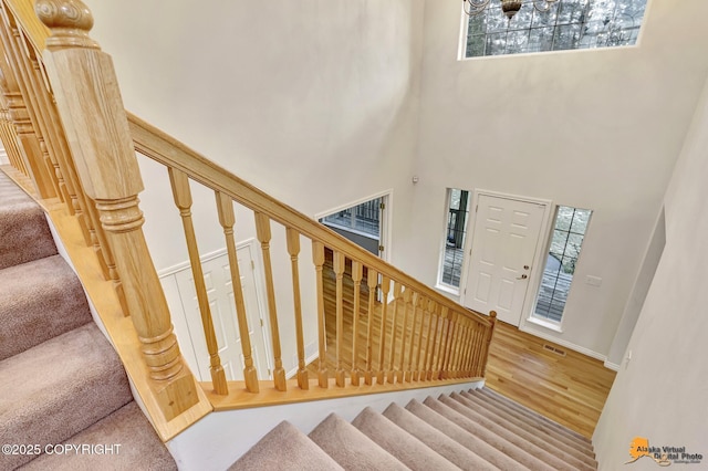 stairway featuring hardwood / wood-style floors, plenty of natural light, and a towering ceiling