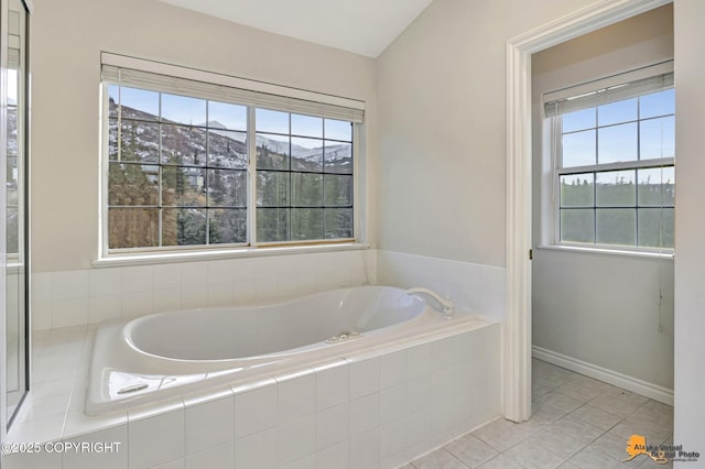 bathroom with a mountain view, tiled bath, plenty of natural light, and tile patterned flooring