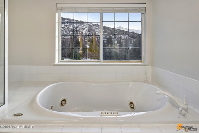 bathroom featuring tiled tub, a mountain view, and a healthy amount of sunlight