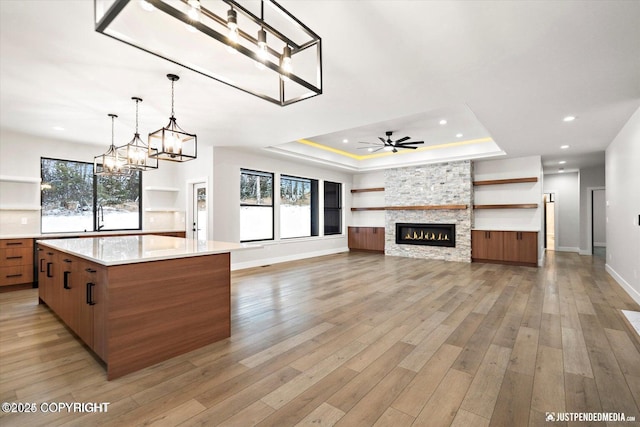 kitchen featuring a healthy amount of sunlight, a fireplace, a raised ceiling, and a spacious island