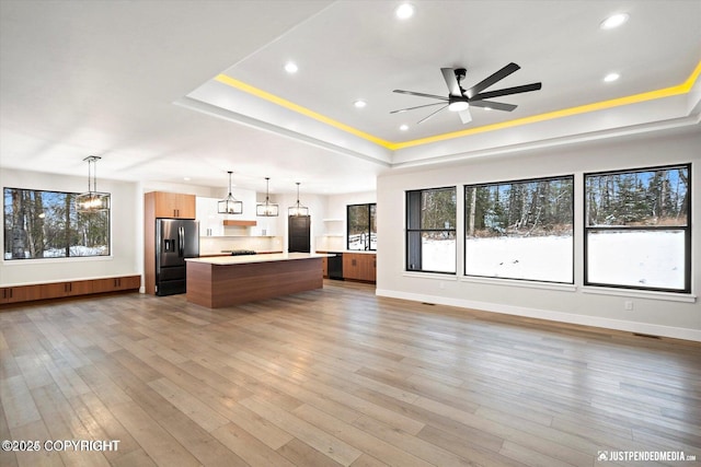 unfurnished living room with ceiling fan, hardwood / wood-style floors, and a raised ceiling