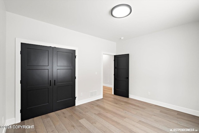 unfurnished bedroom with a closet and light hardwood / wood-style floors