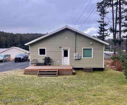 back of house with a wooden deck and a lawn