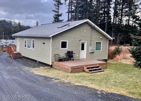 back of property featuring a deck and a lawn