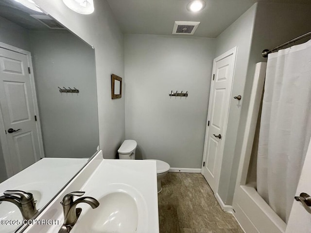 full bathroom featuring wood-type flooring, sink, shower / bath combination with curtain, and toilet