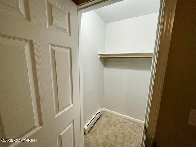 walk in closet with light carpet and a baseboard heating unit