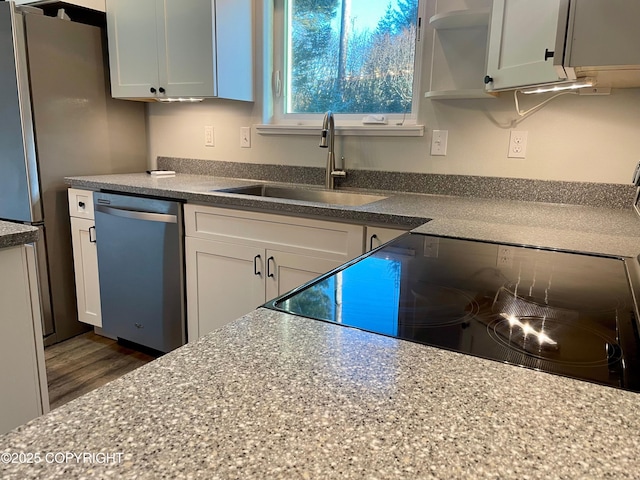 kitchen featuring stainless steel dishwasher, range, sink, and white cabinets