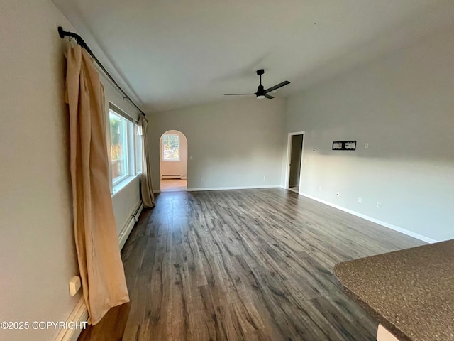 spare room featuring vaulted ceiling, dark hardwood / wood-style floors, ceiling fan, and baseboard heating