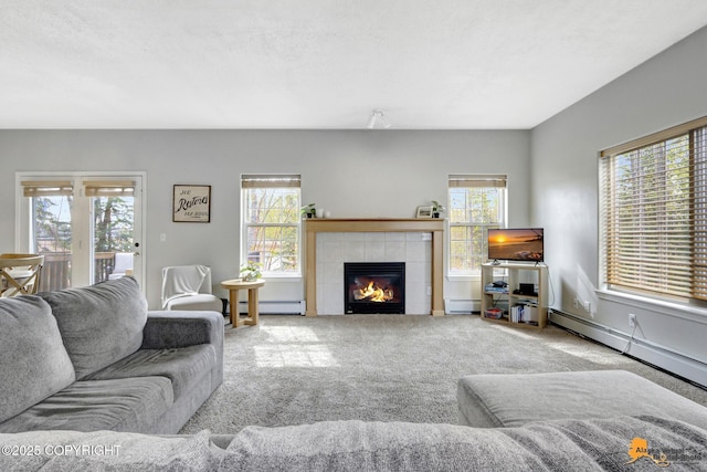 living room featuring carpet flooring, a fireplace, a baseboard radiator, and a healthy amount of sunlight