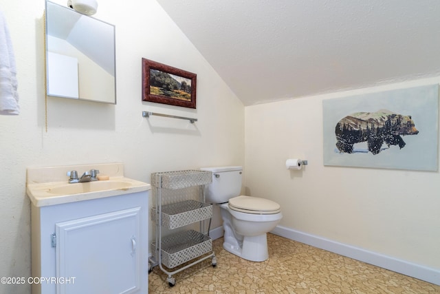 bathroom with toilet, vanity, a textured ceiling, and vaulted ceiling