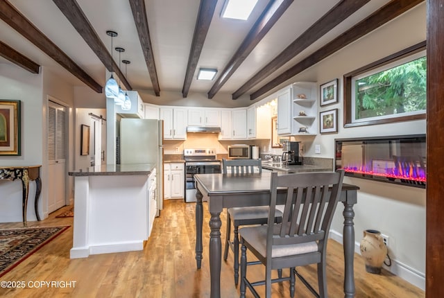 kitchen featuring white cabinets, beamed ceiling, light hardwood / wood-style flooring, kitchen peninsula, and appliances with stainless steel finishes