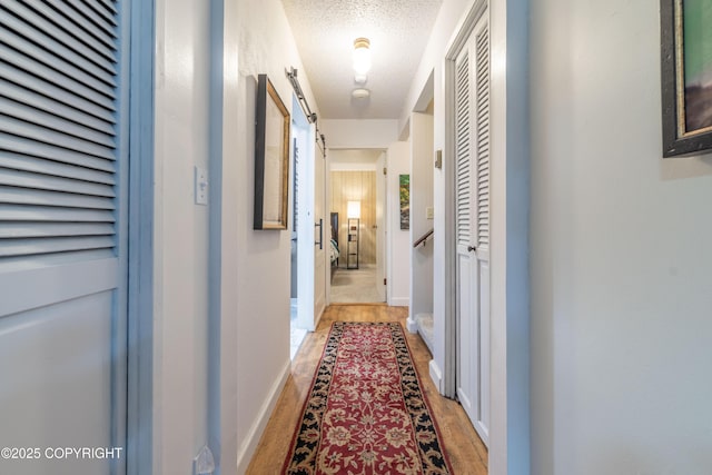 corridor featuring hardwood / wood-style flooring, a textured ceiling, and a barn door