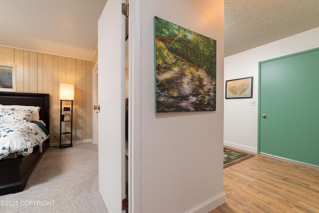 carpeted bedroom featuring a textured ceiling and wood walls