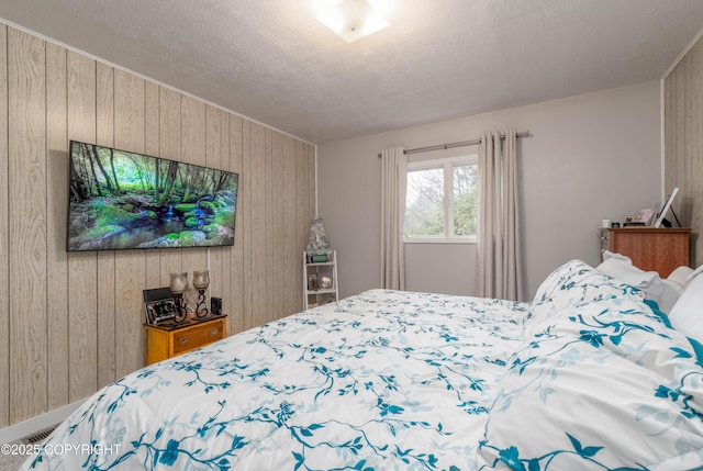 bedroom featuring wooden walls and a textured ceiling