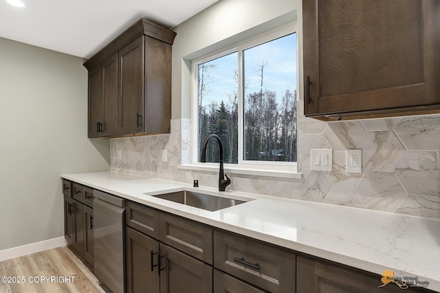 kitchen featuring light hardwood / wood-style floors, backsplash, stainless steel dishwasher, dark brown cabinetry, and sink