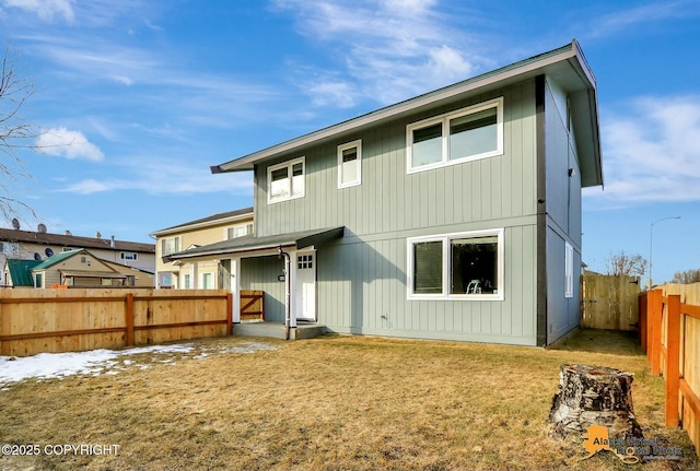 rear view of house featuring a lawn and a fenced backyard