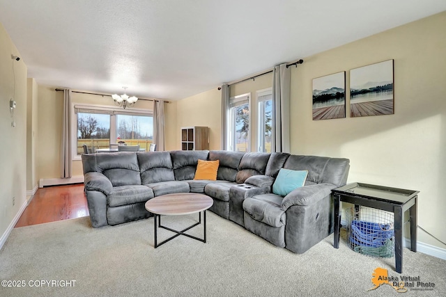 carpeted living area with a baseboard radiator, plenty of natural light, a notable chandelier, and baseboards