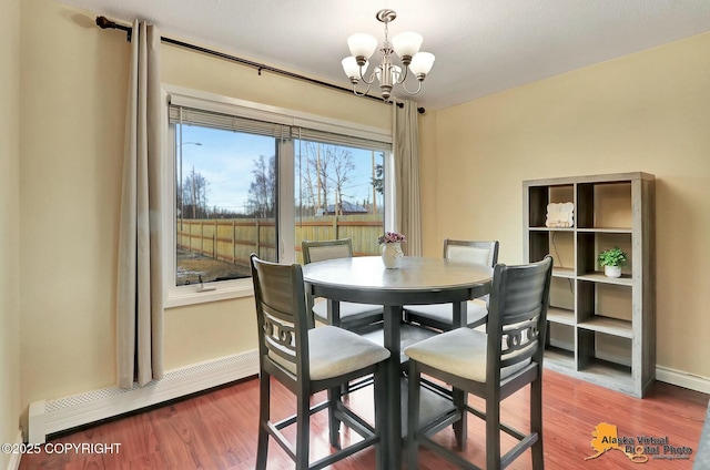 dining area with a baseboard heating unit, baseboards, wood finished floors, and a chandelier