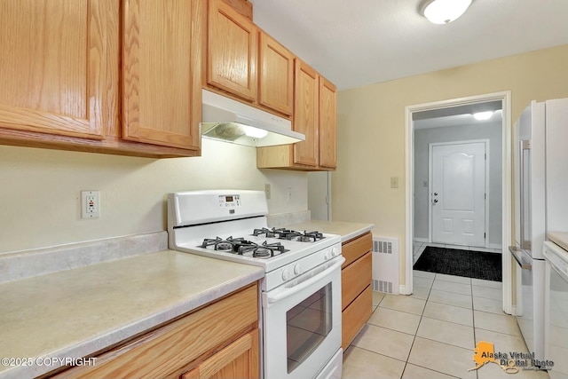 kitchen featuring light brown cabinets, under cabinet range hood, white appliances, light countertops, and light tile patterned floors