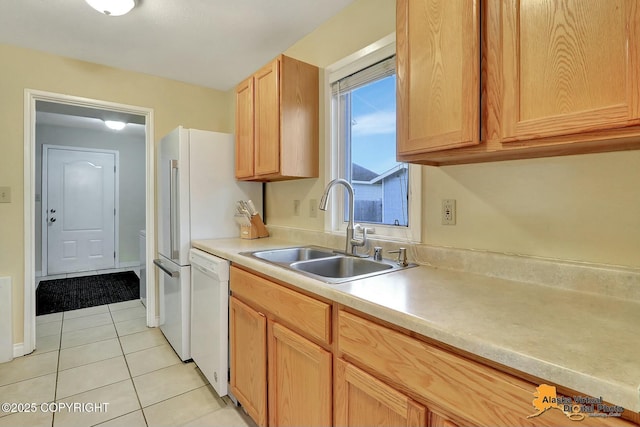 kitchen featuring light brown cabinetry, light countertops, light tile patterned floors, white dishwasher, and a sink