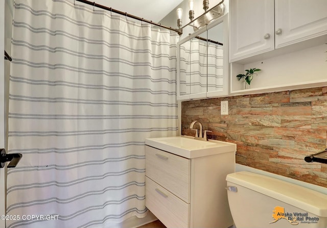 full bathroom with a shower with shower curtain, brick wall, toilet, and vanity