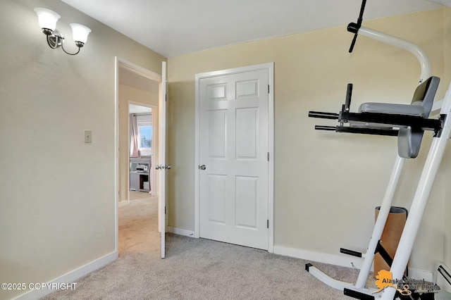 workout area featuring a baseboard heating unit, baseboards, and light colored carpet