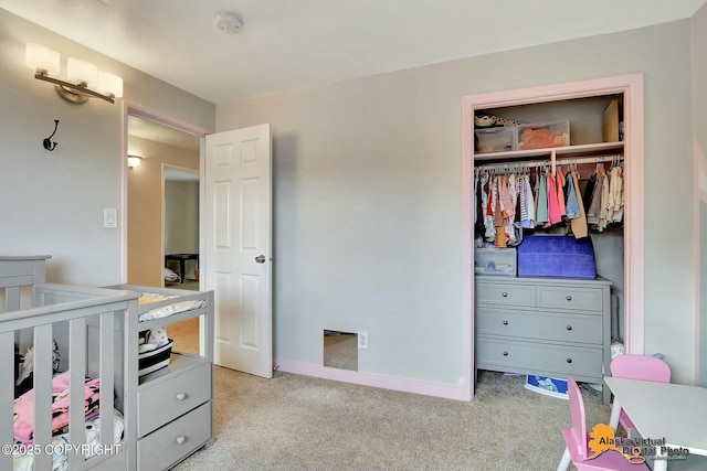 bedroom with a closet, light carpet, and baseboards