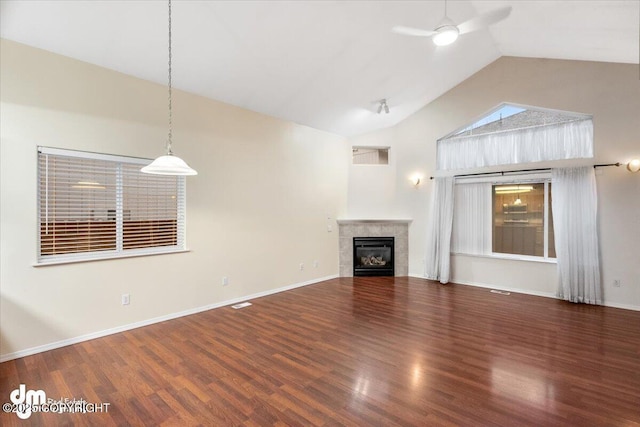 unfurnished living room featuring ceiling fan, a tiled fireplace, dark hardwood / wood-style flooring, and lofted ceiling