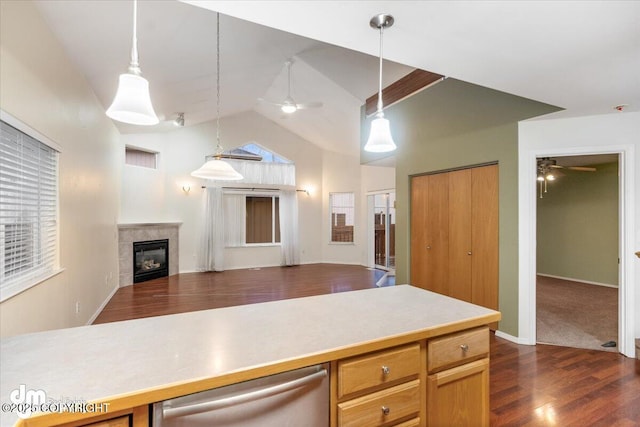 kitchen with dishwasher, hanging light fixtures, a tile fireplace, vaulted ceiling, and dark hardwood / wood-style floors