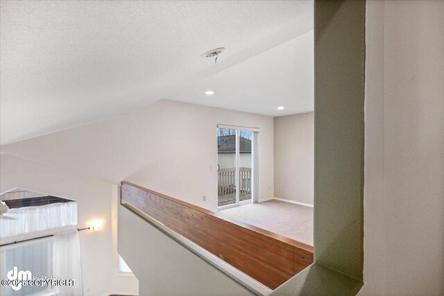 hall featuring a textured ceiling and lofted ceiling