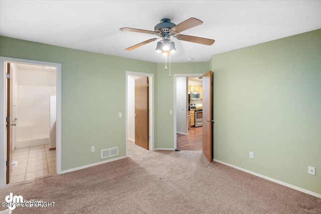 unfurnished bedroom featuring ceiling fan, light colored carpet, and ensuite bathroom