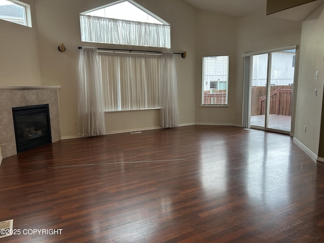 unfurnished living room featuring plenty of natural light, dark hardwood / wood-style floors, and a fireplace