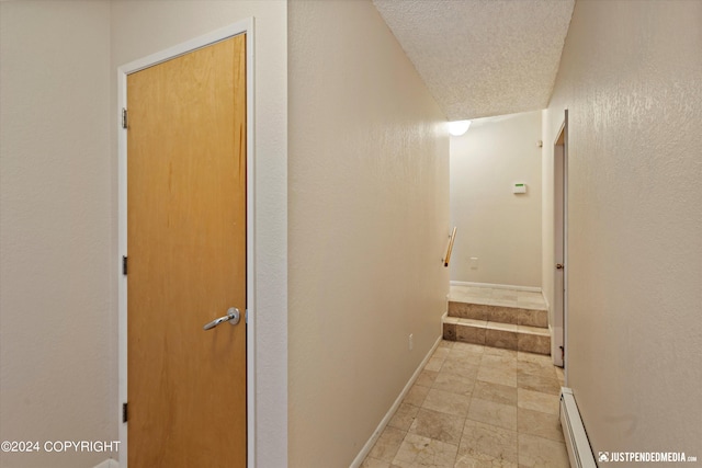 hallway featuring a textured ceiling and a baseboard heating unit