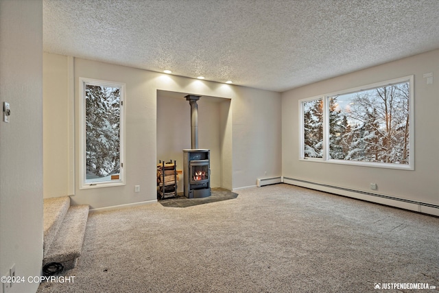 unfurnished living room with carpet, a textured ceiling, a wood stove, and baseboard heating