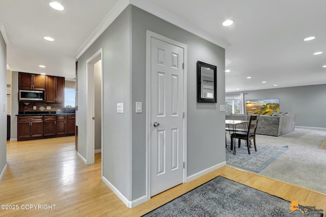 hall featuring crown molding, recessed lighting, baseboards, and light wood-style floors