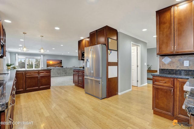 kitchen featuring tasteful backsplash, light wood-type flooring, open floor plan, and stainless steel fridge