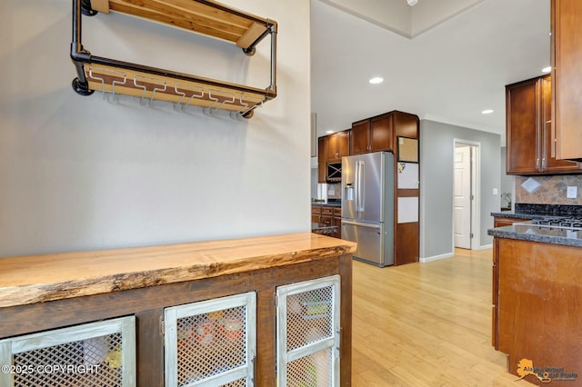 kitchen with tasteful backsplash, stainless steel fridge with ice dispenser, crown molding, light wood-style floors, and recessed lighting