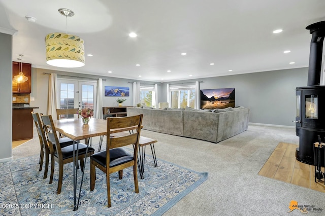 dining area featuring light carpet, ornamental molding, a wood stove, french doors, and recessed lighting