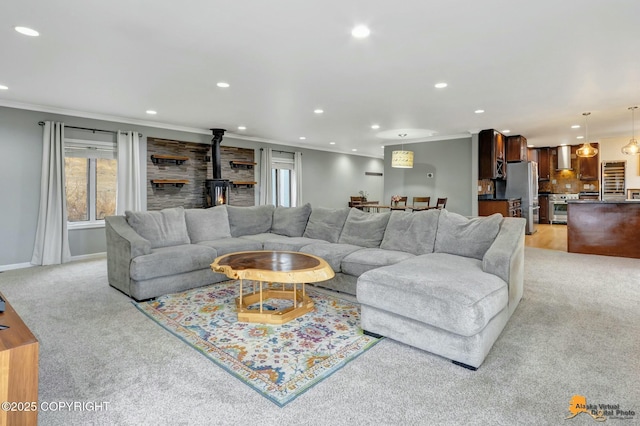 living room with recessed lighting, light carpet, baseboards, a wood stove, and crown molding