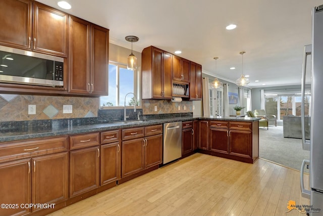 kitchen with tasteful backsplash, pendant lighting, stainless steel appliances, and a sink