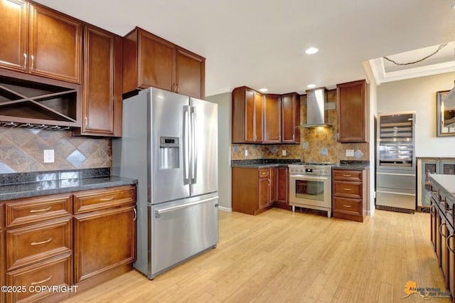 kitchen with light wood-style floors, backsplash, wall chimney exhaust hood, high end appliances, and crown molding