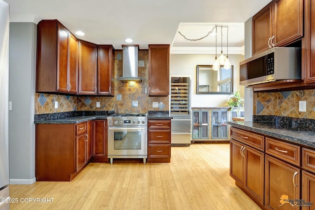 kitchen featuring light wood finished floors, wall chimney exhaust hood, stainless steel appliances, and decorative backsplash