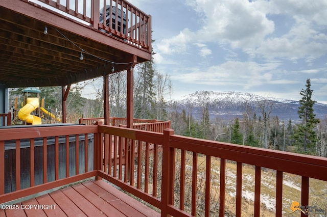 wooden deck with a playground and a mountain view