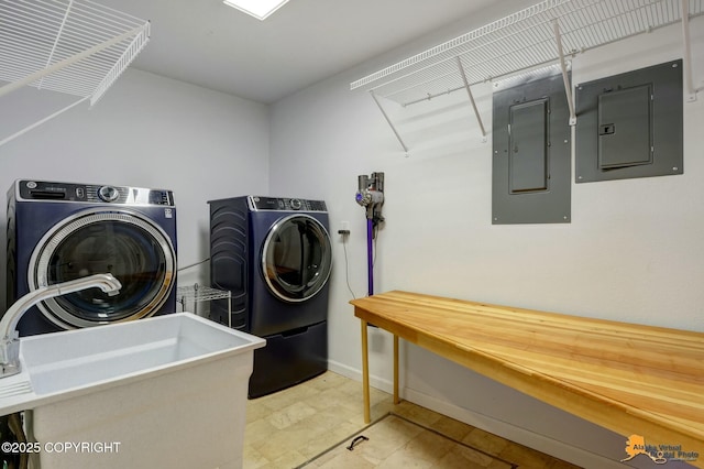 laundry area with laundry area, washing machine and dryer, electric panel, and a sink