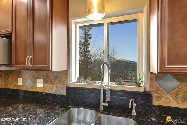 kitchen with a wealth of natural light, dark stone counters, a sink, and decorative backsplash