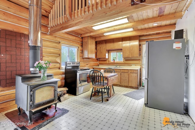 kitchen featuring log walls, stainless steel appliances, a wood stove, and a wealth of natural light